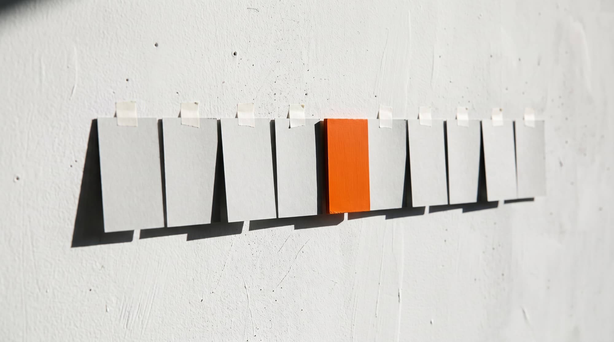 Nine identical blank cards in a row on a chalk wall, the fourth one orange, like frames waiting to render