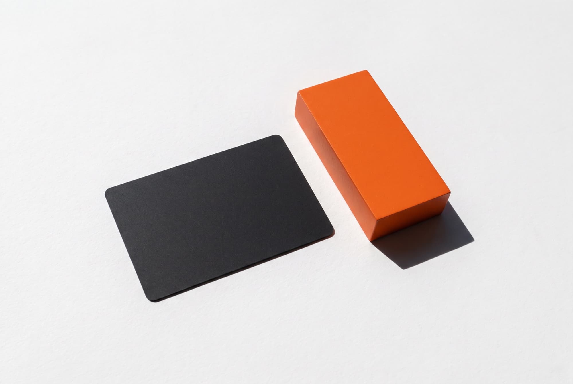 A blank charcoal card and a single orange block lying on paper, photographed from overhead